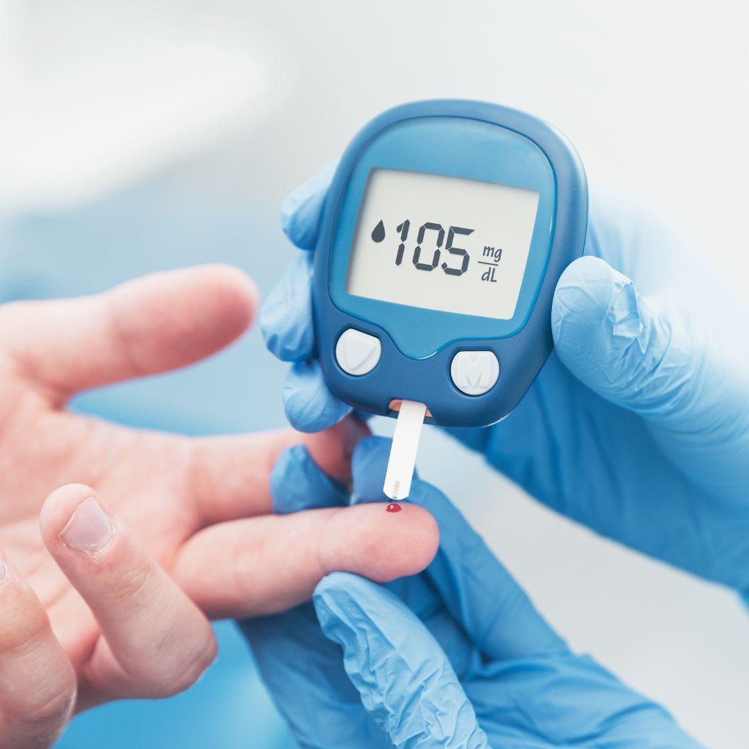 someone in gloves helping someone else take their blood sugar with a glucose monitor