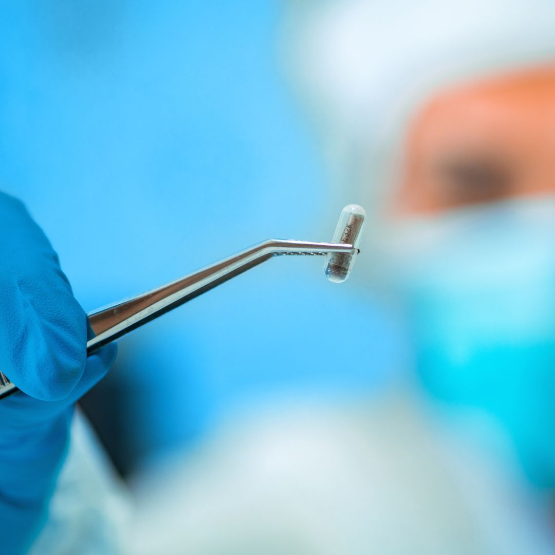 a person in scrubs holding a impantable glucose sensor